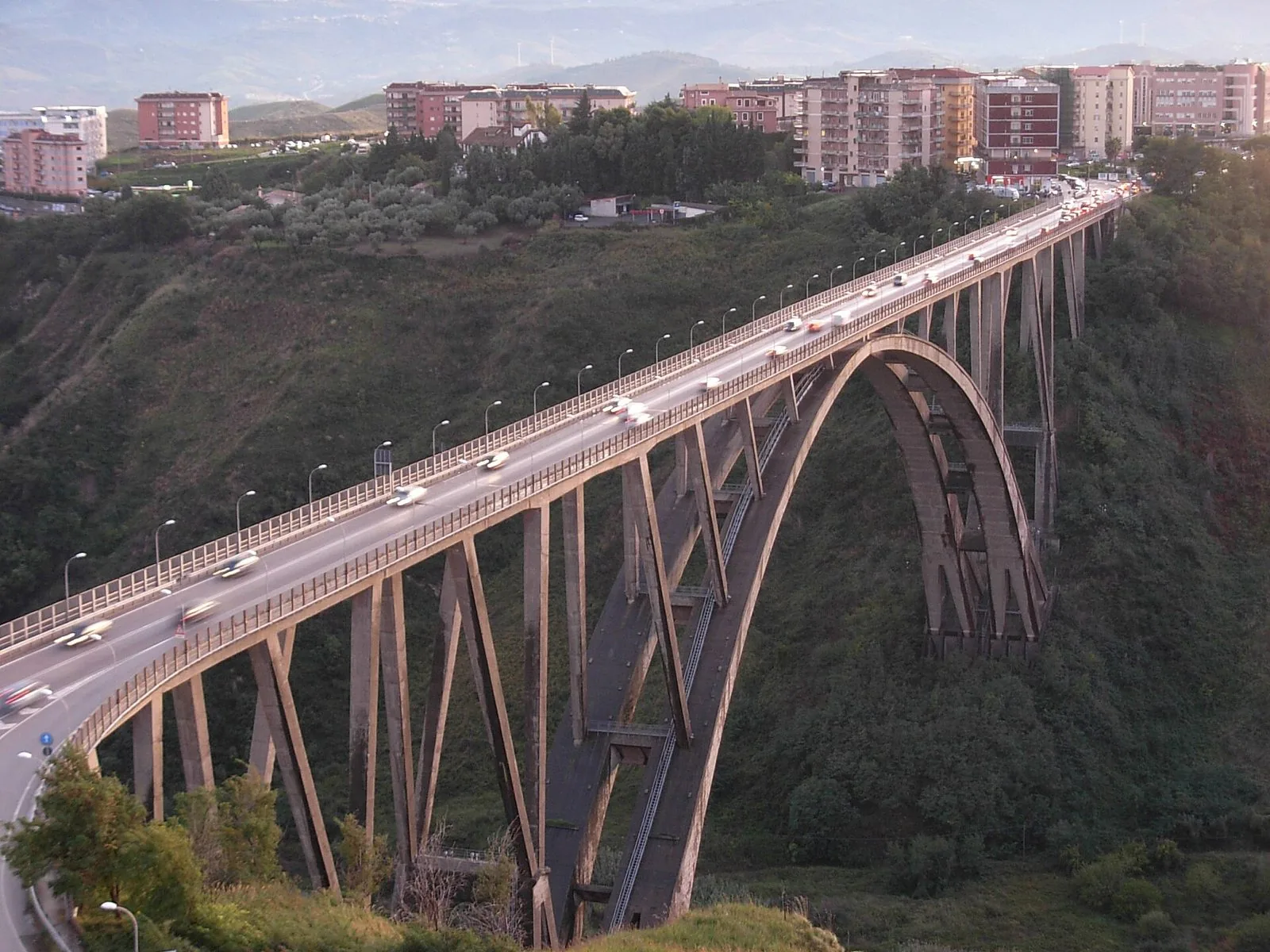 Il Ponte Bisantis di Catanzaro con la grande arcata in cemento sopra la valle verde della Fiumarella, le auto in transito e i palazzi della città sullo sfondo